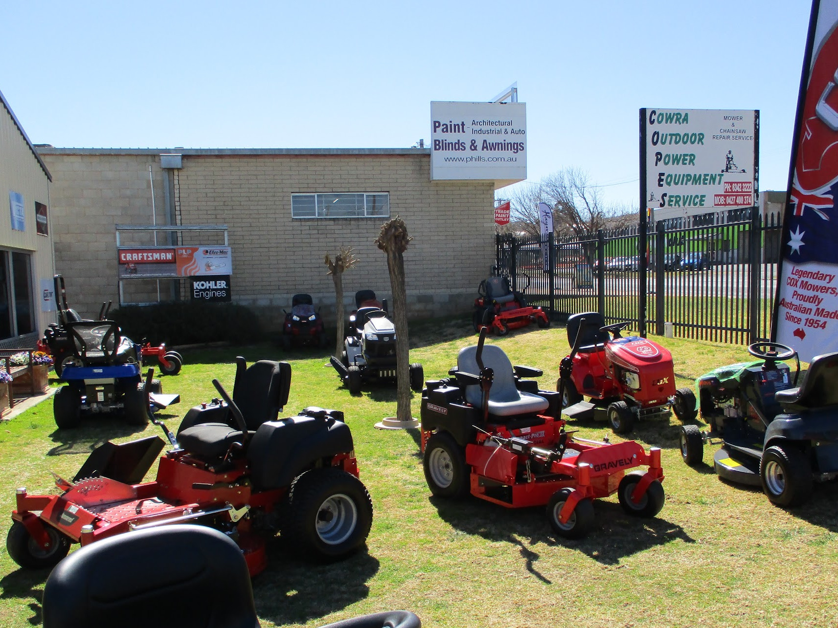 Ride on and zero turn mowers lined up on the grass outside COPES on Redfern Street, Cowra